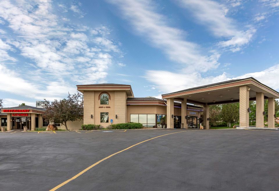 a large parking lot outside a building , with several cars parked in front of the building at Best Western Dunmar Inn