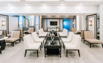 a modern lounge area with white chairs and a black coffee table in front of a large window at Rizal Park Hotel