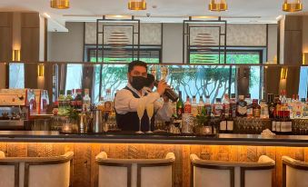 a man in a restaurant is standing behind a bar , holding two champagne glasses and smiling at the camera at Hotel Cabo de Hornos