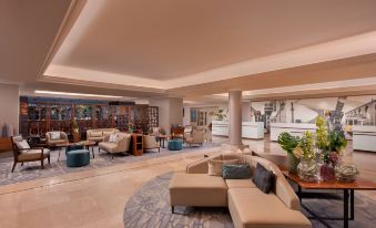 a large , well - lit hotel lobby with multiple couches and chairs arranged for guests to sit and relax at Lisbon Marriott Hotel