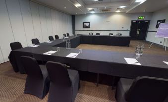 a large conference room with multiple rows of chairs arranged in a semicircle , providing seating for a group of people at Village Hotel Liverpool