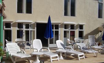 a pool area with a blue umbrella and white chairs arranged around it , creating a relaxing atmosphere at Hotel Presidente
