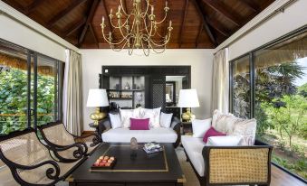 a cozy living room with white couches , a coffee table , and a chandelier hanging from the ceiling at Uga Ulagalla - Anuradhapura