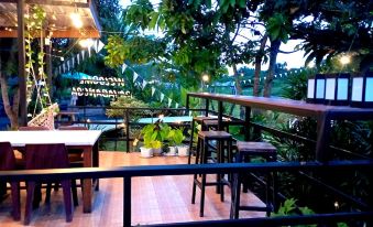 a wooden balcony with a dining table , chairs , and potted plants , overlooking a lush green garden at Payabangsa Resort
