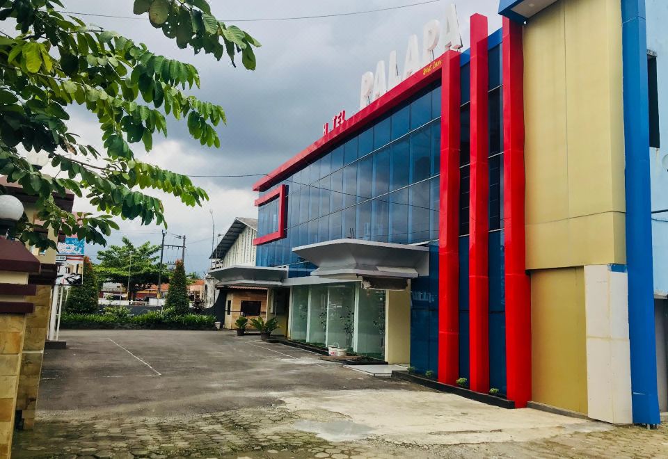 "a large red and blue building with the word "" mein "" prominently displayed on it , surrounded by trees and a parking lot" at Hotel Palapa