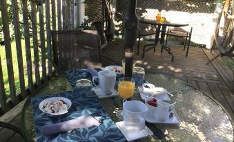 a table is set with a breakfast spread , including plates , bowls , cups , and utensils , on a patio at Garden Studio