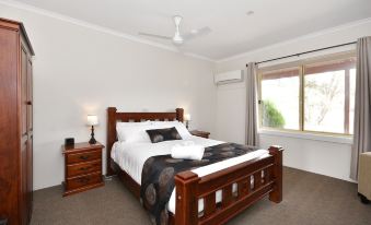 a large bed with a wooden headboard and footboard is in a room with two lamps , a window , and a couch at Inglewood Motel and Caravan Park Victoria