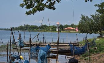 a group of blue fishing nets are hanging on a wooden platform near a body of water at Khun Naparn Resort