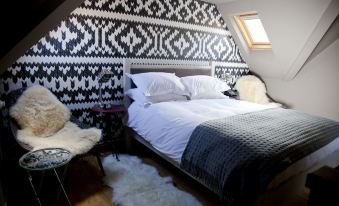 a bed with white and gray bedding is situated in a room with a black and white patterned wall at The White Horse