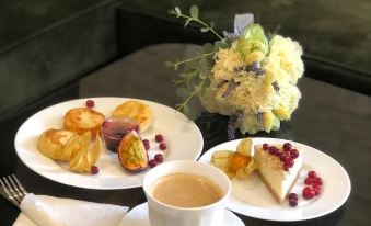 There is a table in the middle with plates, cups, and coffee or tea on it at Mia Milano Hotel