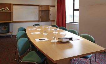 a large conference room with a long wooden table and multiple chairs arranged for a meeting at Ibis Strasbourg Centre Historique