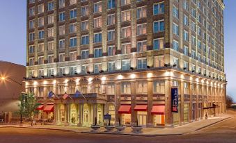 a large hotel building on a city street at night , with multiple windows and balconies at Hilton Garden Inn Jackson Downtown