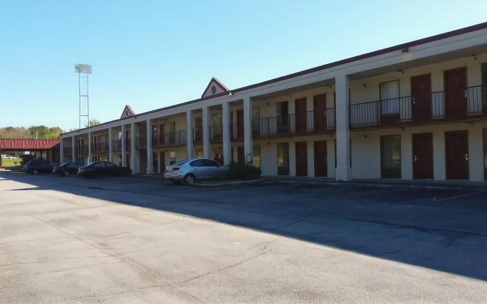 a parking lot with a row of motel buildings and cars parked in front of it at Athens Lodge