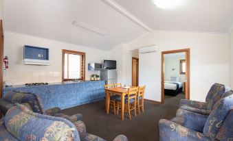 a living room with a dining table , chairs , and a couch is connected to a bedroom at Adelaide Caravan Park - Aspen Holiday Parks