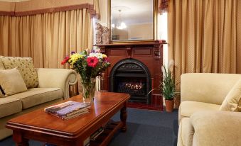 a cozy living room with a fireplace , a wooden coffee table , and several potted plants at Durham Lodge Bed & Breakfast
