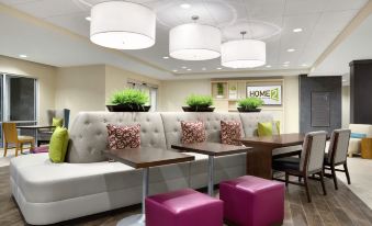a modern office lobby with white and purple furniture , including couches , chairs , and a dining table at Home2 Suites by Hilton Middletown