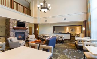 a spacious living room with multiple couches and chairs , a fireplace , and a bar area at Staybridge Suites Buffalo
