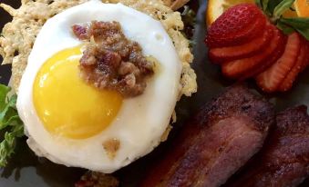 a plate of food with a fried egg , bacon , and other items on a blue plate at Walnut Waters Bed & Breakfast