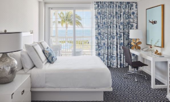 a hotel room with a large bed , white curtains , and a view of the ocean at Isla Bella Beach Resort & Spa - Florida Keys