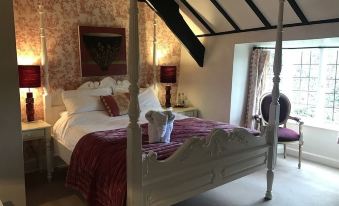 a large bed with a white frame and red bedding is in a room with a wooden headboard and a chandelier at The Nobody Inn