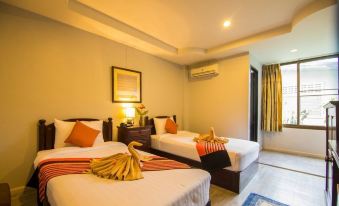 a hotel room with two beds , each bed having orange and yellow striped pillows , along with a nightstand and window at Blue Lagoon Hotel