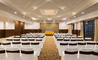 a well - lit conference room with rows of chairs arranged in a semicircle , ready for a meeting or event at Sangam Hotel, Thanjavur
