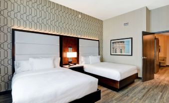 a hotel room with two beds , a nightstand between them and a framed picture on the wall at Embassy Suites by Hilton Plainfield Indianapolis Airport