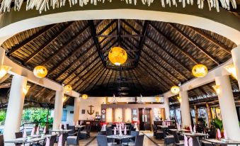 a restaurant with a thatched roof and dining tables surrounded by chairs , creating a cozy atmosphere at Bahia del Sol Beach Front Boutique Hotel
