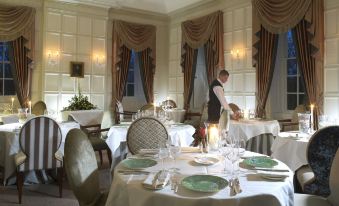 a man in a restaurant setting , preparing for a meal , with tables set up for diners at Ston Easton Park