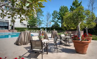 an outdoor dining area near a pool , with several tables and chairs arranged for guests to enjoy their meals at Hyatt Regency San Francisco Airport