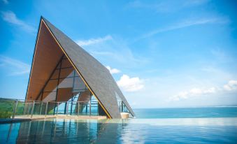 a modern building with a triangular roof , situated on the edge of a body of water at Laut Biru Resort Hotel