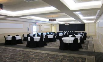 a large conference room with rows of tables and chairs , black and white tablecloths , and a projector screen at Holiday Inn Portsmouth Downtown