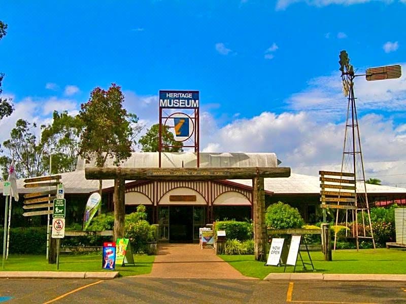 "a large building with a sign that says "" heritage museum "" is surrounded by trees and other structures" at Mareeba Motor Inn