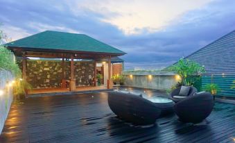 a rooftop patio with a hot tub and a dining table , surrounded by trees and lit up at night at Kautaman Hotel