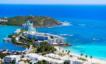 a bird 's eye view of a coastal city with white buildings , blue water , and palm trees at Oyster Bay Beach Resort