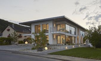 a modern , two - story house with a large window and multiple balconies , situated on a street with green grass and trees at Lumina Apartments