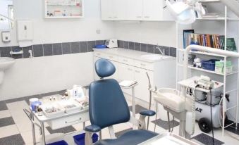 a dental office with a blue chair in the center of the room , surrounded by various dental tools and equipment at Hotel Arborétum