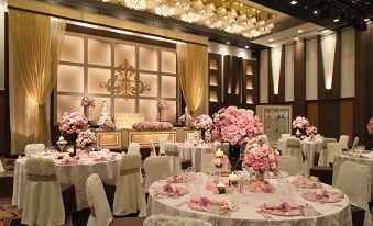 a formal dining room with a table set for a wedding reception , featuring white tablecloths , pink flowers , and multiple chairs at Hotel Metropolitan Yamagata