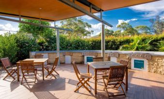 an outdoor patio with a dining table , chairs , and umbrellas , providing shade and comfort for people enjoying their outdoor space at Ingenia Holidays Lake Conjola