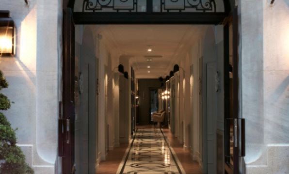 a long hallway with a door at the end and a sign on the right side at Hotel Bachaumont