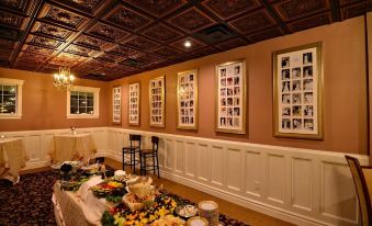 a room with a table covered in food and framed pictures on the wall , as well as chairs and a chandelier at Avon Inn