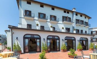 a large white building with balconies and a patio area featuring potted plants and chairs at Hotel Jaccarino