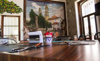 a wooden table with a vase of flowers and silverware in front of a mural at Casa San Miguel Hotel Boutique y Spa