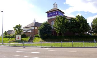 "a brick building with a blue sign that says "" executive inn "" is surrounded by trees and a road" at Premier Inn Gillingham Business Park