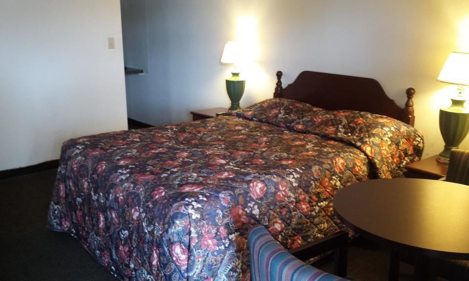 a bed with a floral comforter is situated next to a nightstand and lamp in a hotel room at H&K Motel