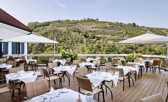 an outdoor dining area with tables and chairs set up on a wooden deck , overlooking a vineyard at Steigenberger Hotel and Spa, Krems