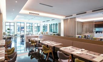 a modern restaurant with wooden booths , chairs , and tables , as well as a bar area at Hilton Garden Inn Puchong