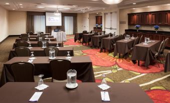 a conference room with rows of tables and chairs , a projector screen , and a watermark on the screen at Hilton Garden Inn Merrillville