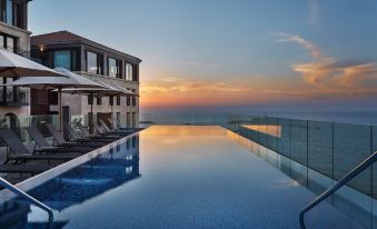 a large outdoor pool with a building in the background and lounge chairs around it at The Setai Tel Aviv, a Member of the Leading Hotels of the World