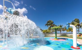 a large outdoor pool surrounded by palm trees , with a water fountain in the center of the pool at Moon Palace Jamaica